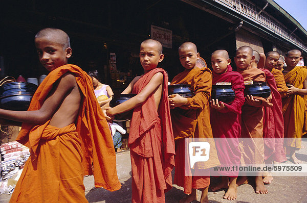 Young Buddhist monks carrying bowls in the street  Yangon (Rangoon)  Myanmar (Burma)  Asia
