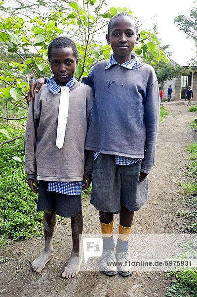 Two schoolboys in make-do school uniform  one barefoot  with white cotton fabric pinned in place of school tie  Langalanga Primary School  Gilgil district  Rift Valley  Kenya  East Africa  Africa