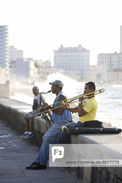 Musicians on The Malecon playing saxaphone and trombone with waves crashing against the shore in the background  Havana  Cuba  West Indies  Caribbean  Central America