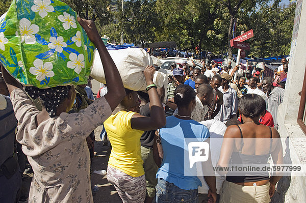 Women carrying sacks of rice at food distribution after the January 2010 earthquake  Port au Prince  Haiti  West Indies  Caribbean  Central America