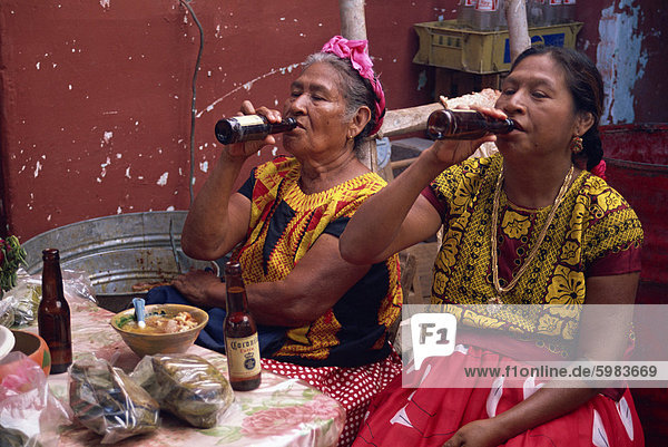 Portrait of two Mexican women in traditional clothing  drinking bottled beer  sitting at a table  Mexico  North America