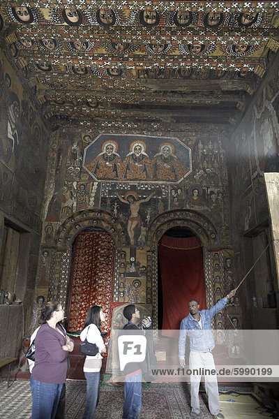 Ein Leitfaden zeigt Touristen die kirchliche Kunstwerke schmücken die Wände der Debre Berhan Selassie Kirche  Gondar  Äthiopien  Afrika