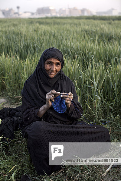 Eine Frau sitzt in einem Feld auf der Luxor Westbank  Ägypten  Nordafrika  Afrika stricken