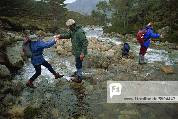 Hikers crossing river in the Ben-Damph Hills  near Loch Torridan  Highlands  Scotland  United Kingdom  Europe