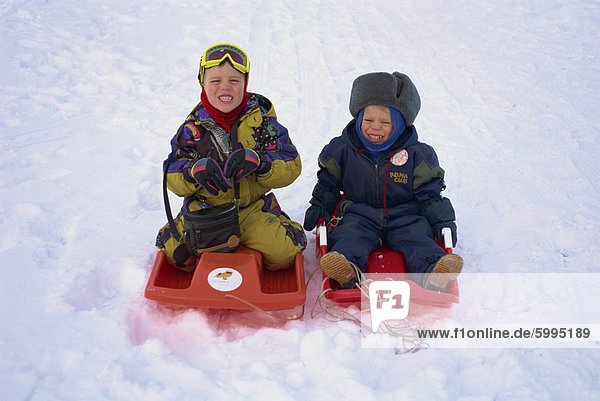 Two children on red toboggans playing in the snow in Finland  Scandinavia  Europe