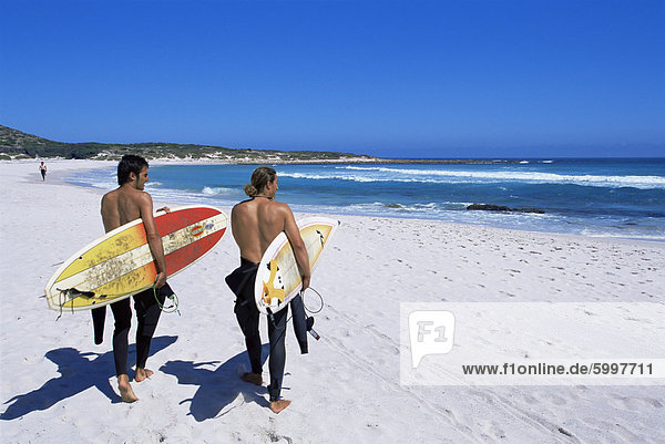 Two surfers walking with their boards on Kommetjie beach  Cape Town  South Africa  Africa