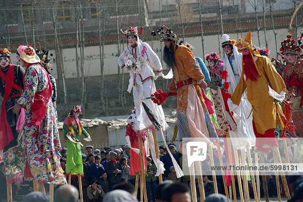 Stilt dancers in parade at New Year celebrations in Qinghai Province  China  Asia