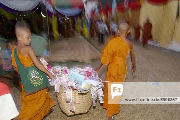 Two young monks carrying basket of donations during the Pha That Luang Festival during Buddhist Lent  at the Great Stupa in Vientiane  Laos  Indochina  Southeast Asia  Asia