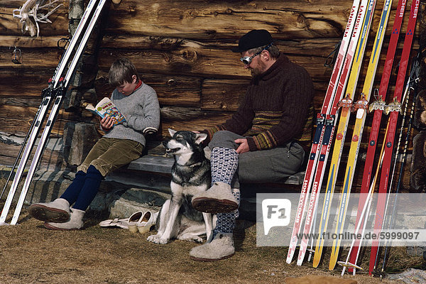 Mann mit seinem Hund und junge liest ein Buch sitzen draußen  an der Setra  Solveggen Pa Setra  Norwegen  Skandinavien  Europa