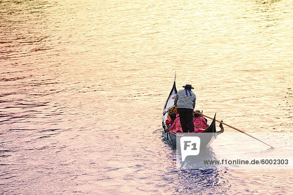 Gondola at sunset carrying passengers across the Grand Canal by St. Marks Square  Venice  Veneto  Italy  Europe