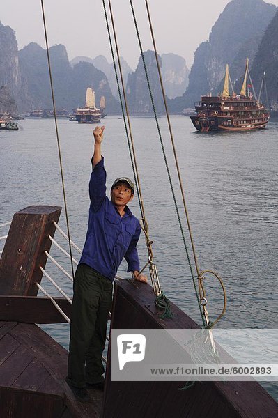 Crewman raises anchor on junk Ha Long Bay  Vietnam  Indochina  Southeast Asia  Asia