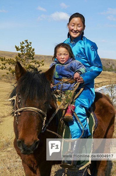 Junge mongolische Frau und Kind in Tracht (Deel) Reiten ein Pferd  Provinz Chowd  Mongolei  Zentralasien  Asien