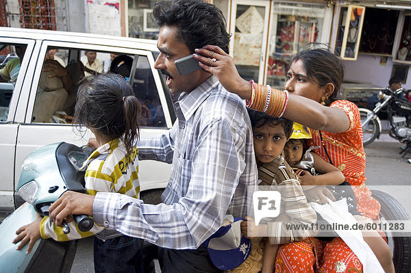 Familie von fünf auf Roller  Frau hält Handy für Ehemann zu rufen  Udaipur  Rajasthan  Indien  Asien