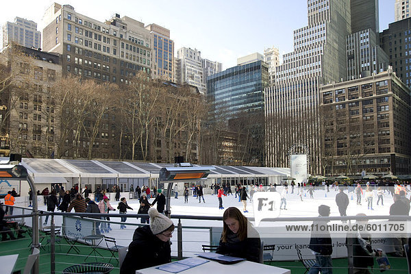 Leute sitzen in einem Café neben der Eislauffläche im Bryant Park  New York City  New York State  Vereinigten Staaten von Amerika  Nordamerika