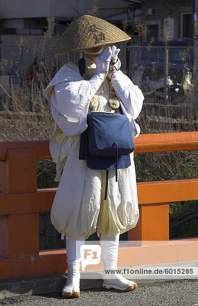 Pilgrim wearing traditional hat and white clothes standing on a bridge and praying  near Fushimi Inari Taisha shrine  Kyoto  Kansai  Honshu  Japan  Asia