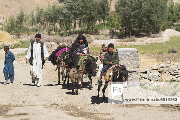 Aimaq people walking and riding donkeys entering village  Pal-Kotal-i-Guk  between Chakhcharan and Jam  Afghanistan  Asia