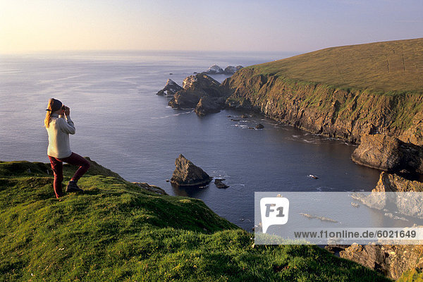 Birdwatching on cliffs of Hermaness Nature Reserve  looking north towards Vesta Skerry  Tipta Skerry gannetry  Muckle Flugga and its lighthouse in the distance  Unst  Shetland Islands  Scotland  United Kingdom  Europe