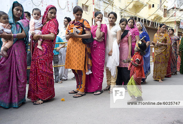 Women queueing for Diwali temple puja  being approached by a child begging for alms  Udaipur  Rajasthan  India  Asia