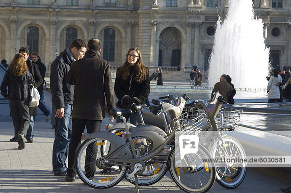 Touristen am Brunnen vor dem Louvre mit gemieteten Velib Fahrräder  Paris  Frankreich  Europa