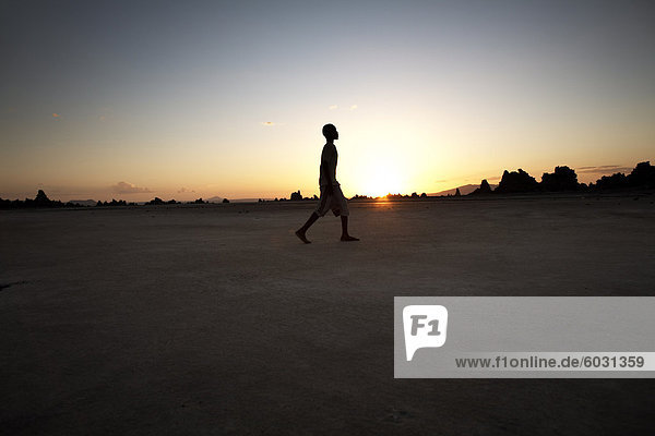 A boy walks through the desolate landscape of Lac Abbe  Djibouti  Africa