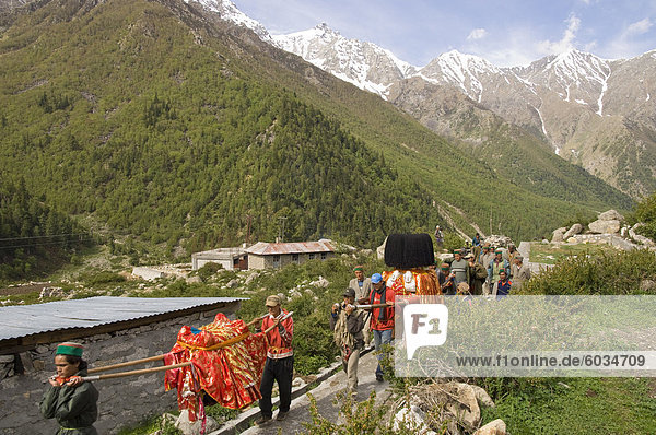 Tägliche Puja religiöse Prozession mit lokalen Gottheiten im Tal mit den schneebedeckten Bergspitzen im Hintergrund Chitkul 3460m Baspa Valley Kinnaur Himachal Pradesh Indien Asien