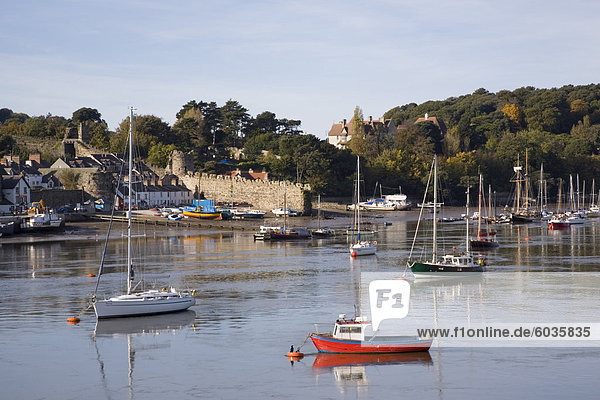 View across river estuary to town wall quay and harbour with moored boats on calm water  Conwy  Wales  United Kingdom  Europe