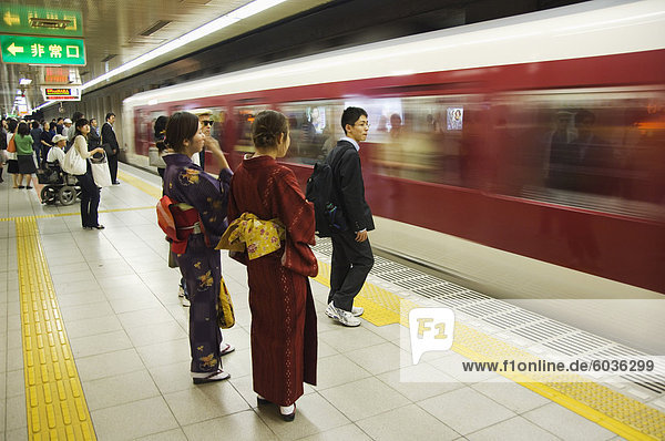Young women wearing kimono waiting for train to arrive at Kyoto Station  Kyoto  Honshu Island  Japan  Asia
