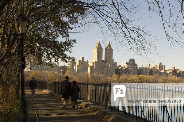 Menschen Wandern neben der Echsenkessel im Central Park im Winter mit hohen Gebäuden von Central Park West in den Hintergrund  New York City  Vereinigte Staaten von Amerika  Nord Amerika