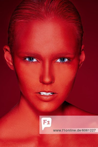 Porträt der jungen Frau mit Gesicht in roten gemalt  Studioaufnahme
