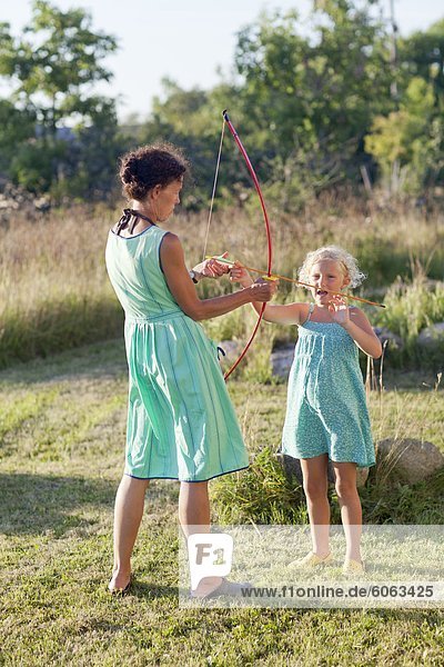 Mutter und Tochter spielen mit Pfeil und Bogen