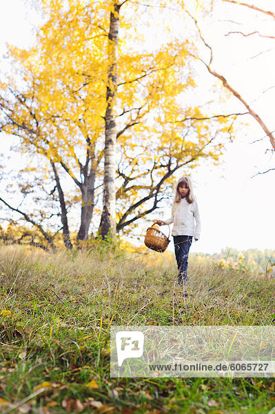 Mädchen gehen durch Herbstliche Landschaft mit Korb