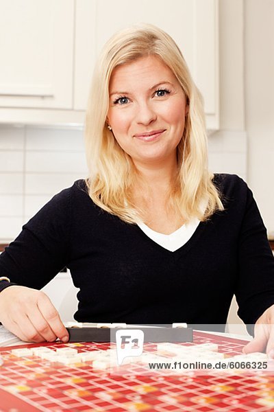 Portrait of young woman playing board game in kitchen