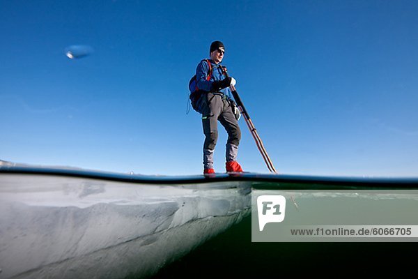 Mann  stehend auf Eis mit pole