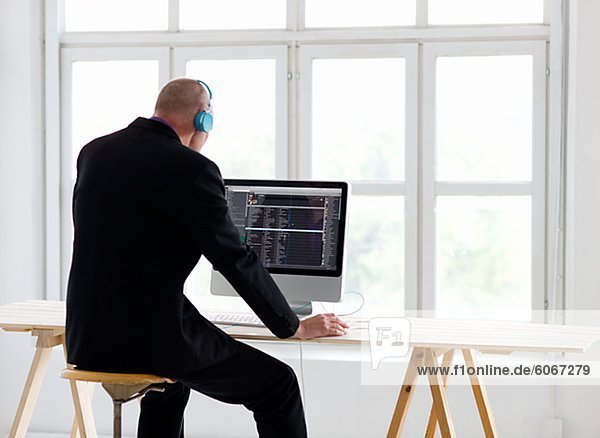 Businessman listening to headphones  using computer in office