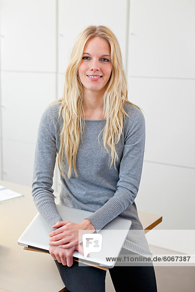 Portrait of woman holding laptop in office