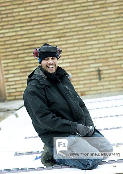 Junge Bauarbeiter kniend auf Dach