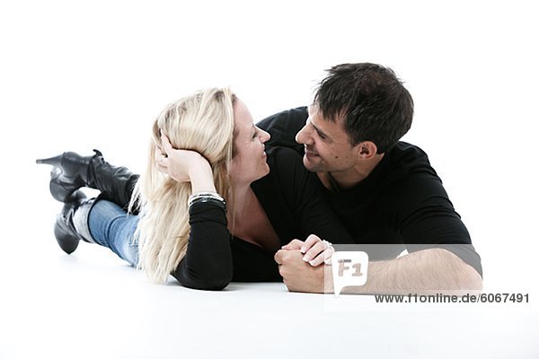 Studioaufnahme des jungen Paares auf Boden  umarmen