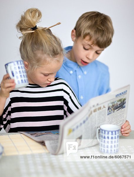 Porträt der jungen und Mädchen lesen Zeitung am Tisch