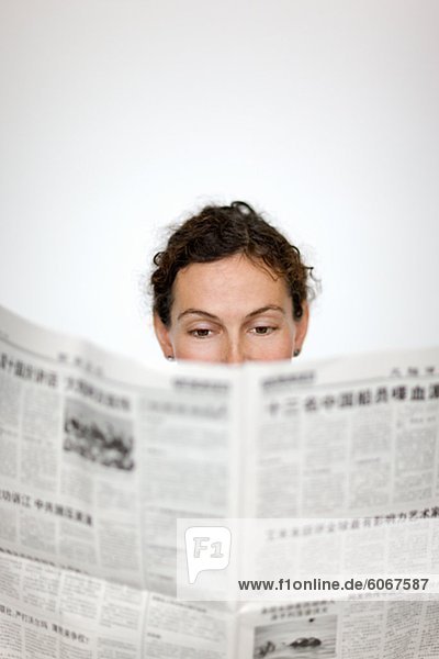 Close up of womans head behind newspaper