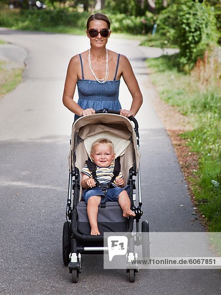 Smiling woman walking with son in pram
