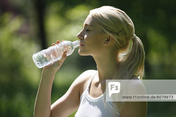 Eine junge Blondine trinken eine Flasche Wasser Nahaufnahme