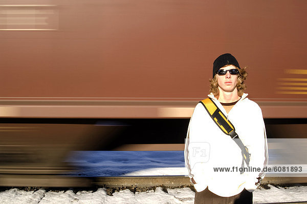 A young man stands as a train goes by behind him in Whitefish  MT.