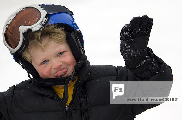 A 4-year-old boy in a ski helmet and goggles smiles and plays.