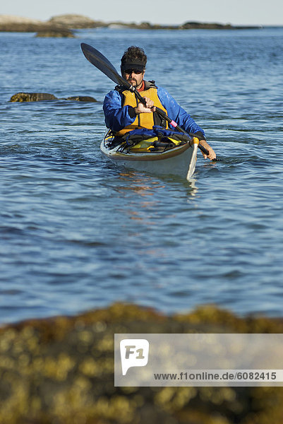 A man sea kayaking on the Maine coast.