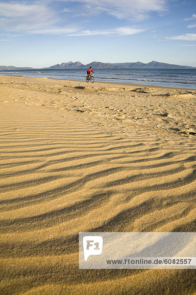 A woman enjoying a bike ride on Nine Mile Beach on the east coast of Tasmania  Australia.