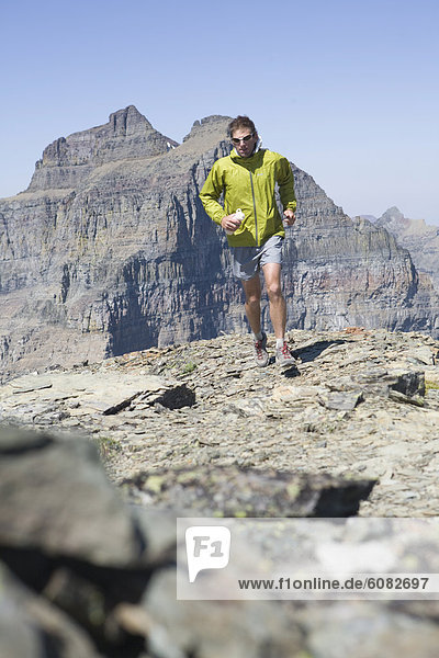 A trail runner makes his way across a rocky path in Glacier National Park.