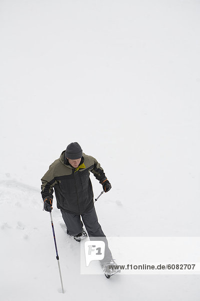 A solo male snowshoer makes his way down a mountain.