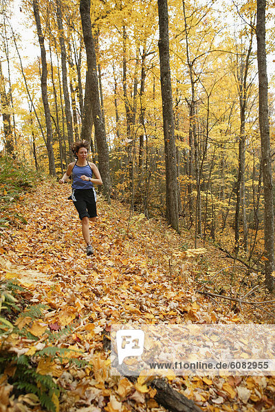 Female trail runner under fall foliage.