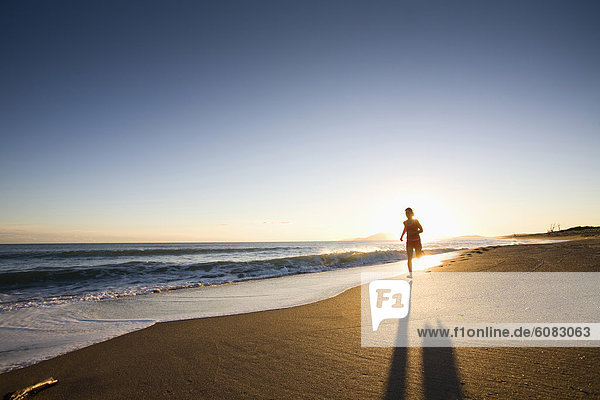 A young woman running at sunset on Chiarone Beach in Tuscany  Italy. (backlit)