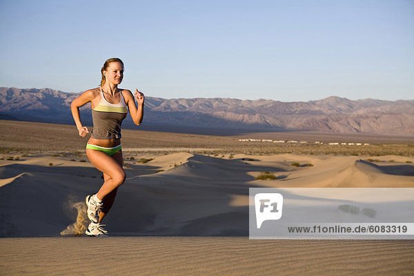 A young woman out for a morning run on the Stovepipe Wells Dunes in Death Valley  California.